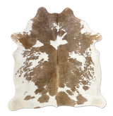 Brown and white cowhide rug on a white background
