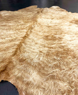 Close-up of a beige cowhide fur rug with a dark background
