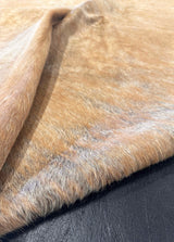 Close-up of brown cowhide fur with a dark background