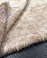 Close-up of cowhide fur with a neutral color palette on a dark background