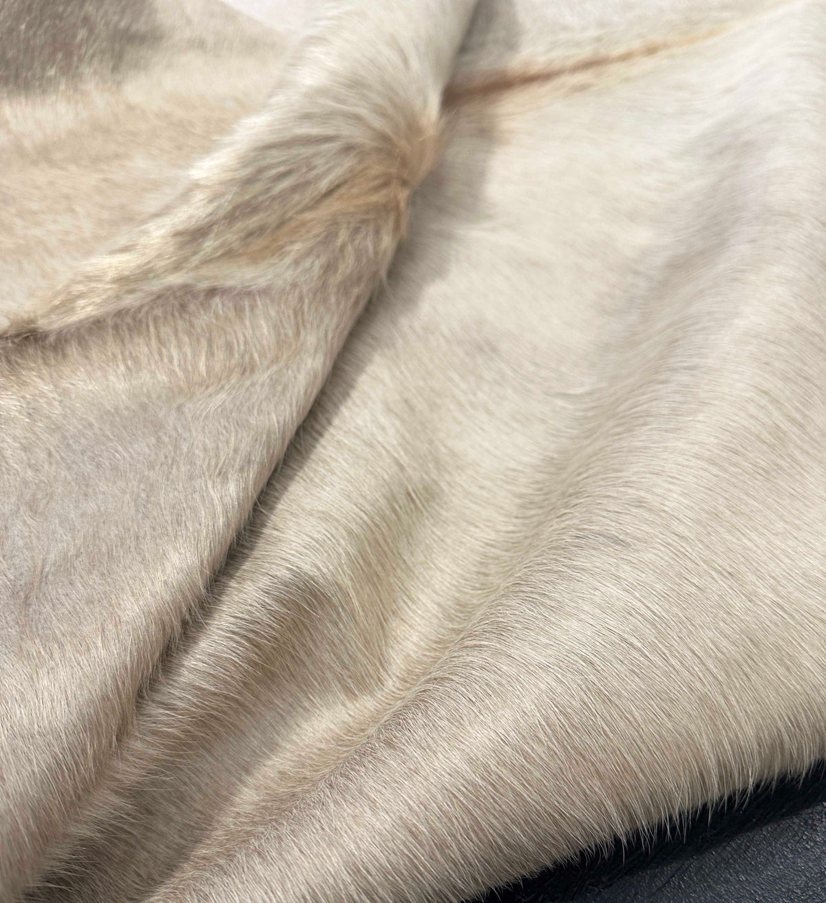 Close-up of a cowhide fur texture with a neutral color palette.