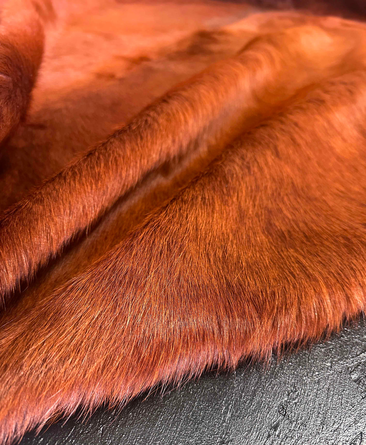 Close-up of terracotta dyed cowhide showing natural hair texture and subtle tonal variation