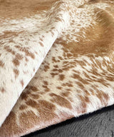 Close-up of a brown and white cowhide rug on a wooden floor.