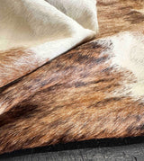 Close-up of brown and white cowhide texture on a dark surface