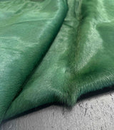 Close-up of green cowhide fur fabric on a textured surface