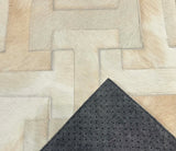 Enchanté stitched cowhide rug sample with a corner turned back to show gray felt backing and black nonslip grip dots