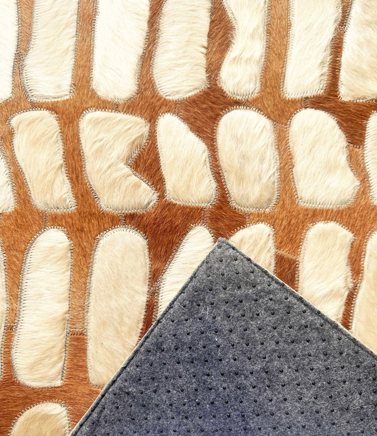 Paros stitched cowhide rug sample showing protective felt backing with discreet rubber grip dots