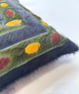 Stitched cowhide pillow detail showing mustard burgundy and olive hide accents