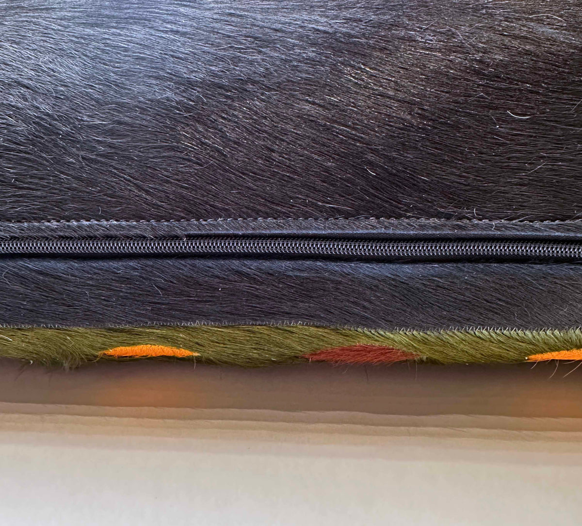 Snake stitched cowhide pillow detail showing hidden zipper and cowhide back