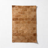Savona 16-by-24-inch cowhide rug sample with staggered 2-by-4-inch rectangles in caramel and honey-tan tones.