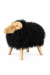 A sheep-shaped art with a fluffy black fur body, a light natural wood head and legs, and curved wooden horns on top, shown on a plain white background.