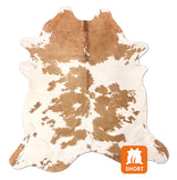 Brown and white cowhide rug on a white background