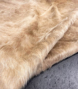 Close-up of beige cowhide fur fabric on a textured gray surface