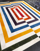 Exact 8-foot by 10-foot stitched cowhide rug with ivory, green, gold, blue, purple, orange, and red bands