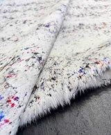 Close-up of a cowhide rug with colorful specks on a gray surface