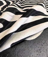 Black and white zebra-patterned cowhide fur fabric draped over a dark textured surface.