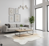 Modern living room with gray sofa, cowhide rug, wooden coffee table, and large windows.