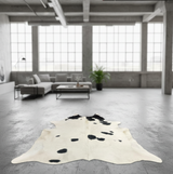 Cow print rug on a concrete floor with large windows in the background