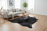 A black cowhide rug staged in a living room