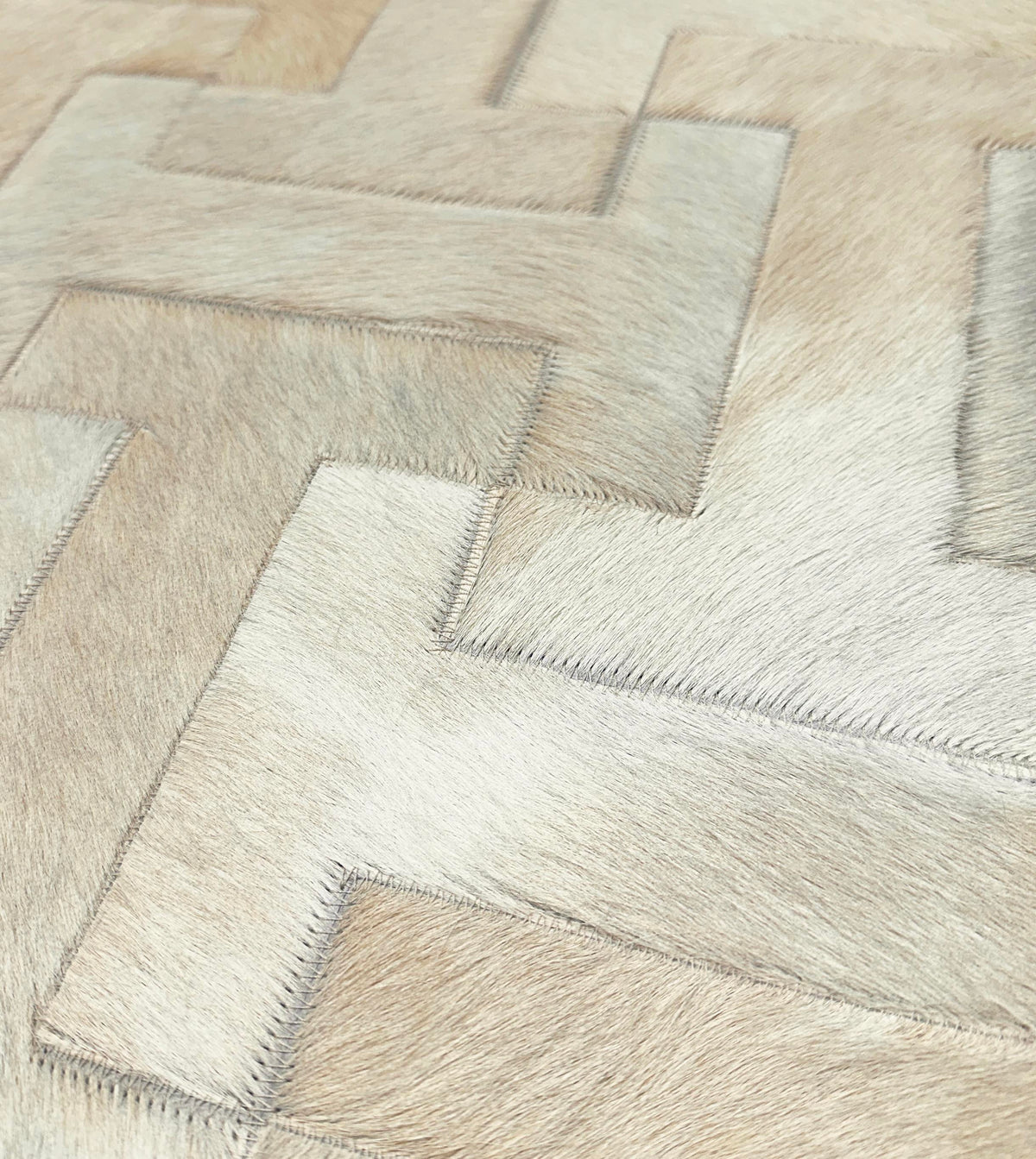 Close-up of Enchanté tonal ivory cowhide pieces with natural hair texture and coordinating zigzag stitching
