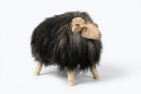 Wooden ram sculpture with black fur on a white background