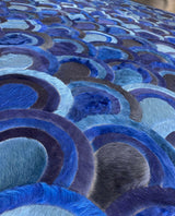 Low-angle detail of the Ocelli rug showing layered navy, cobalt, indigo and pale blue hair-on cowhide