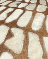 Close-up of ivory cowhide shapes and zigzag stitching on the Paros natural brown cowhide rug