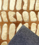 Paros stitched cowhide rug sample with a corner turned back to show gray felt backing and black nonslip grip dots