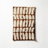 Paros stitched cowhide rug design sample with irregular ivory shapes on natural brown hide
