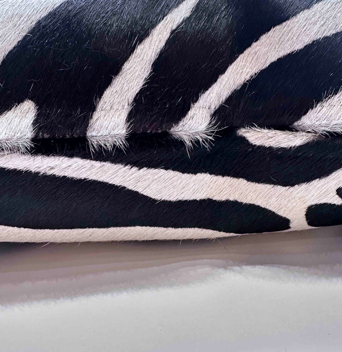 Stenciled zebra cowhide pillow detail showing hidden zipper and black ivory pattern