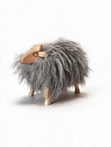A small wooden sheep figurine with a shaggy gray fur body and natural light wood legs, head, and horns, photographed on a clean white background.
