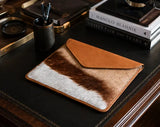 Springbok laptop sleeve on a desk with books and stationery items.