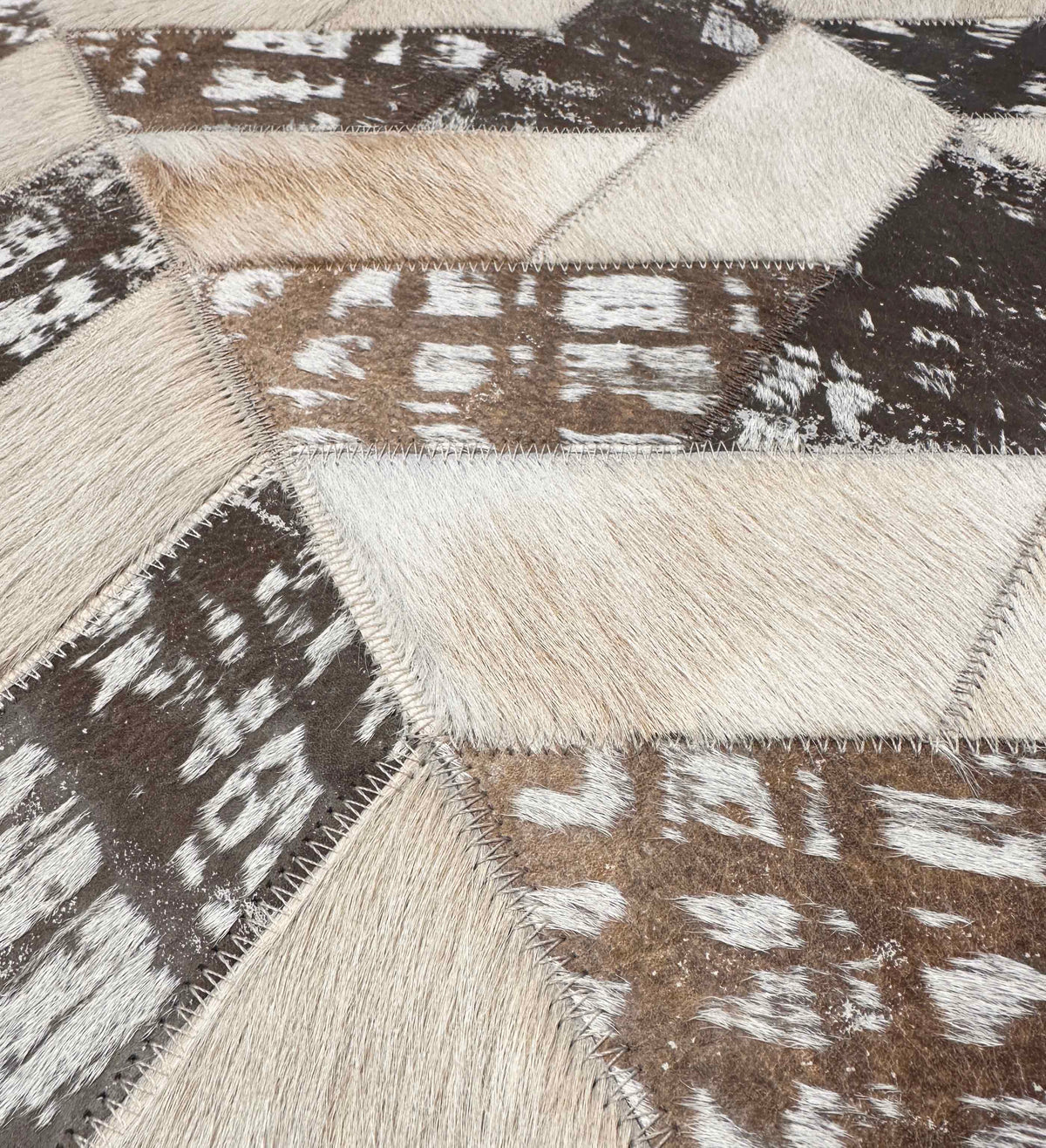 Close-up of Palermo’s light beige and stonewashed brown hair-on cowhide pieces, showing natural markings and zigzag stitching.

