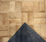 Underside of the Tessaro stitched cowhide rug showing gray felt backing with nonslip grip dots